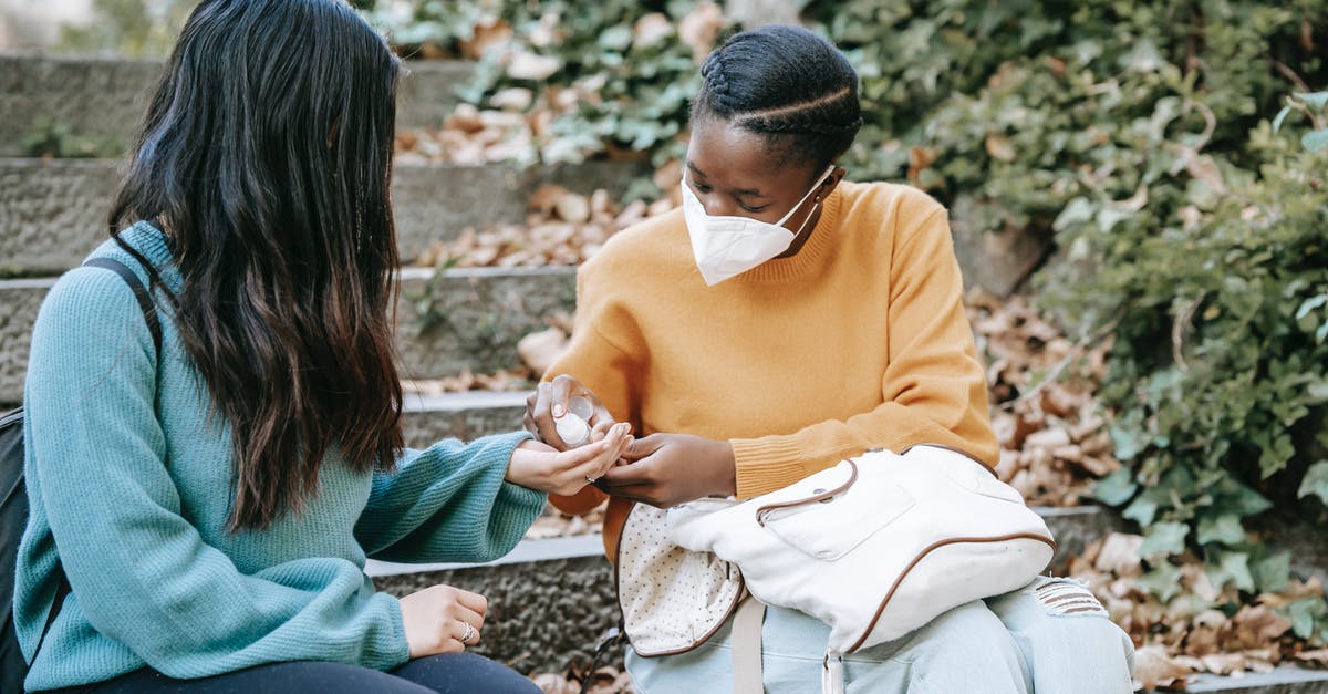 10 year ban after applying for a UK student visa - Unrecognizable ethnic student applying sanitizer on hand of girlfriend outdoors