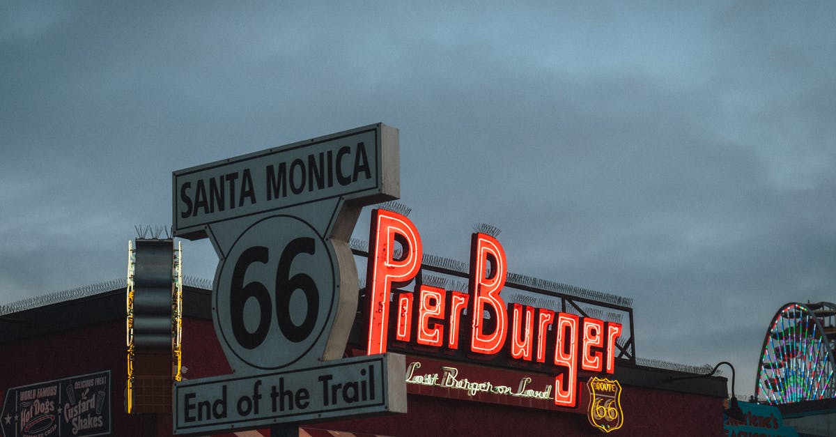 18 hours layover as a South African traveling back from USA - Low angle of road sign with Route 66 End of the Trail inscription located near fast food restaurant against cloudy evening sky on Santa Monica Beach