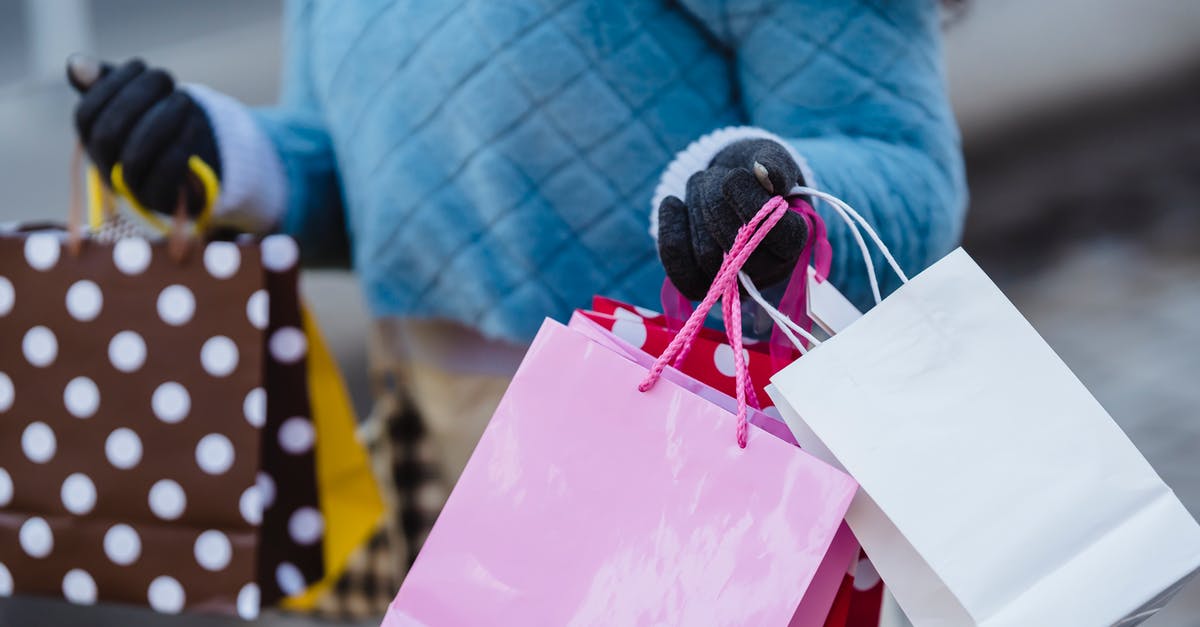 1-week holiday in Fiji. How to carry my cash? - Crop anonymous female in blue soft sweater with many different colorful gift bags on blurred background