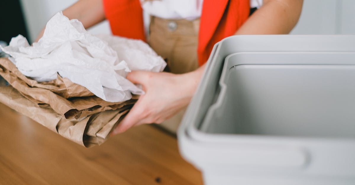 221(g) Administrative Processing: Is this a "refusal/denial?" - Crop anonymous female volunteer in casual clothes holding pile of paper bags while standing near wooden table with plastic container in light room