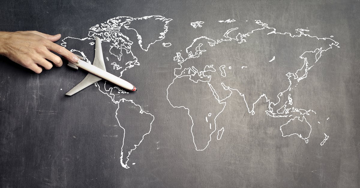 2FABE - the 'secret' international travel postcard stamp code? - From above of crop anonymous person driving toy airplane on empty world map drawn on blackboard representing travel concept