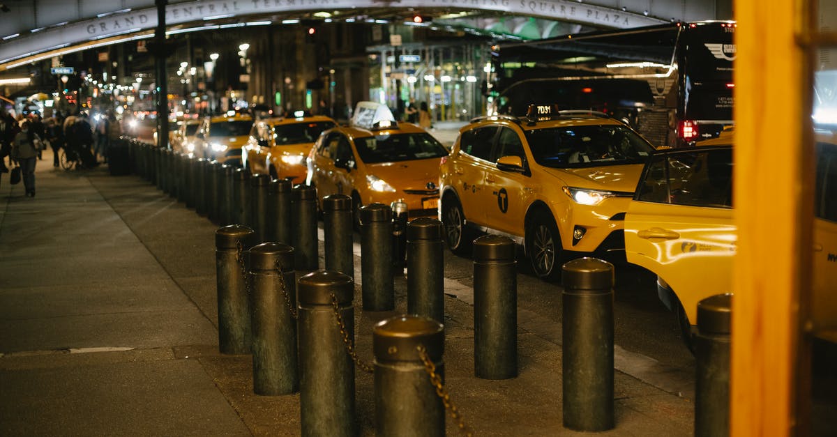 2-hour parking in the US - Row of modern shiny yellow taxis with glowing headlights parked at roadside near Grand Central Terminal in New York at night