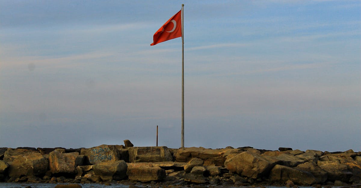 50$ per day requirement for entry into Turkey - Turkish Flag waving over stones near sea