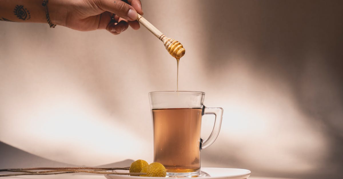 5 kg hard honey in hand luggage? - 
A Person Holding a Honey Dipper over a Beverage