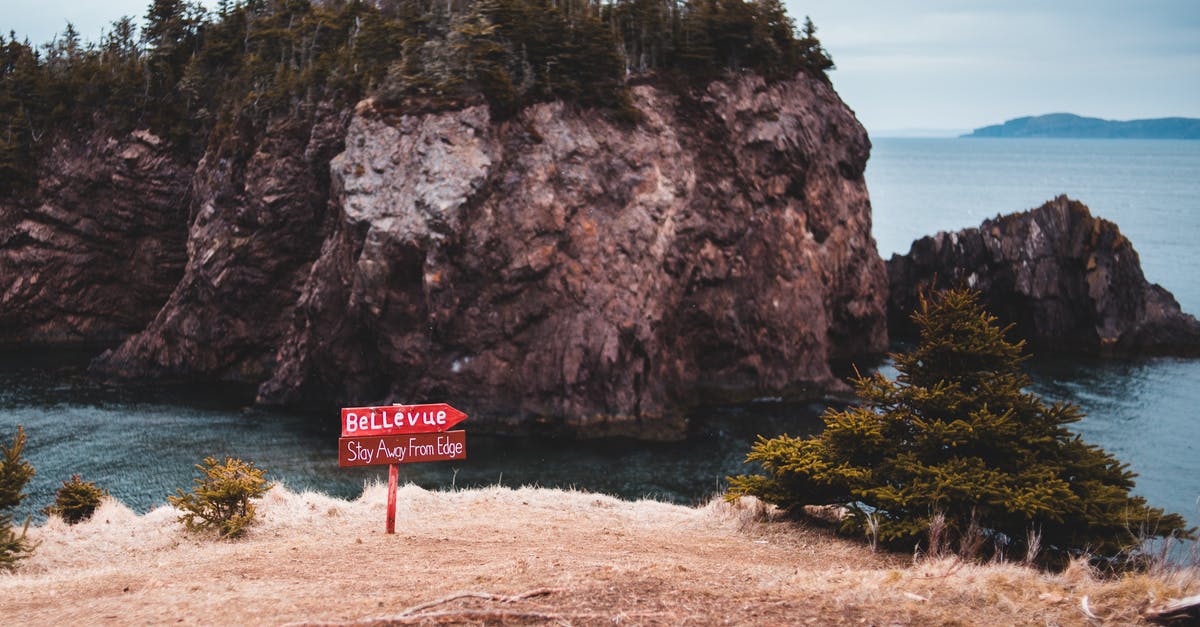 6 month stay in canada - Caution signboard on edge of rocky cliff in front of wild island in sea