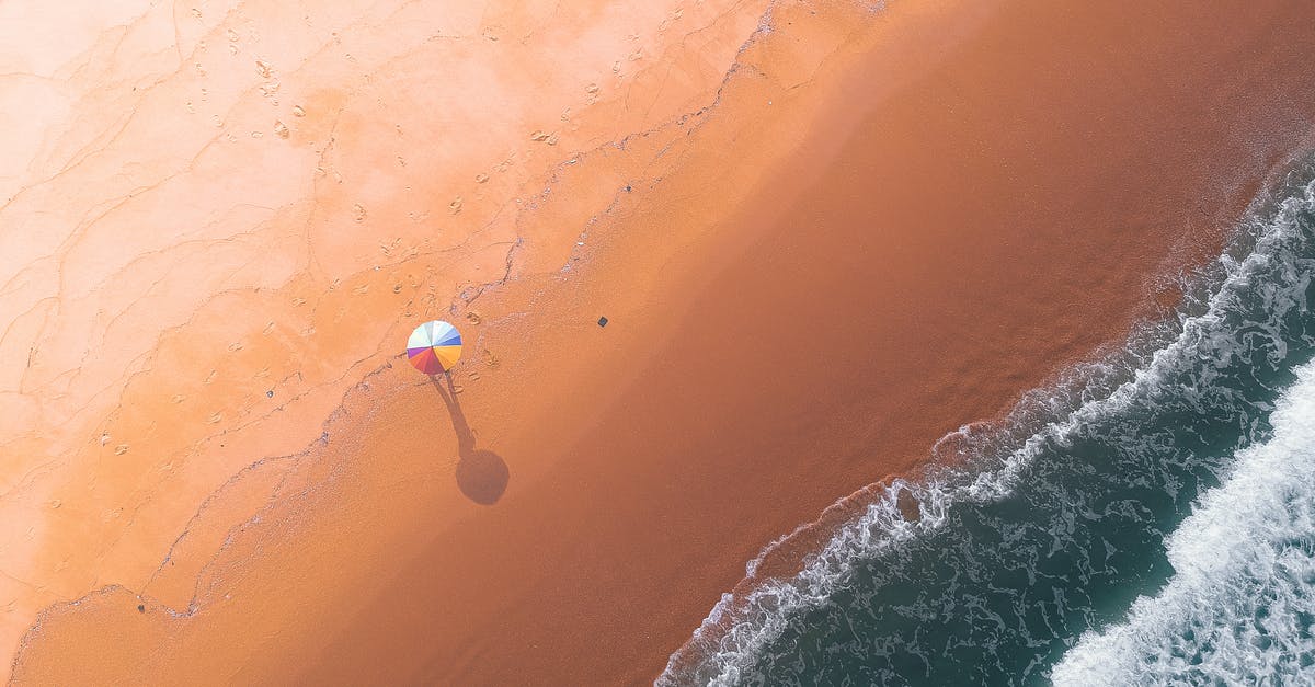 90 day holiday visa for South Korea - Aerial view of sandy beach with colorful umbrella in middle near wavy water in summer sunny day