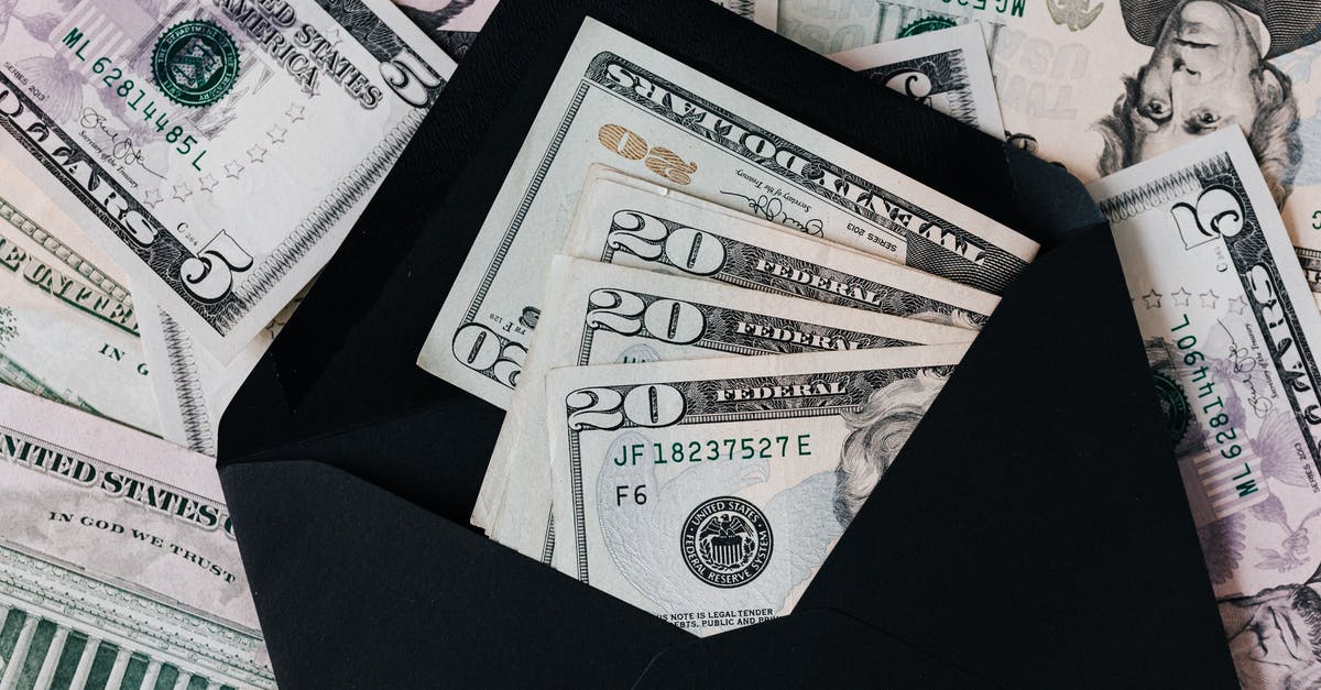 A German visiting Mexico from the US - From above of dollar bills in opened black envelope placed on stack of United states cash money as concept of personal income