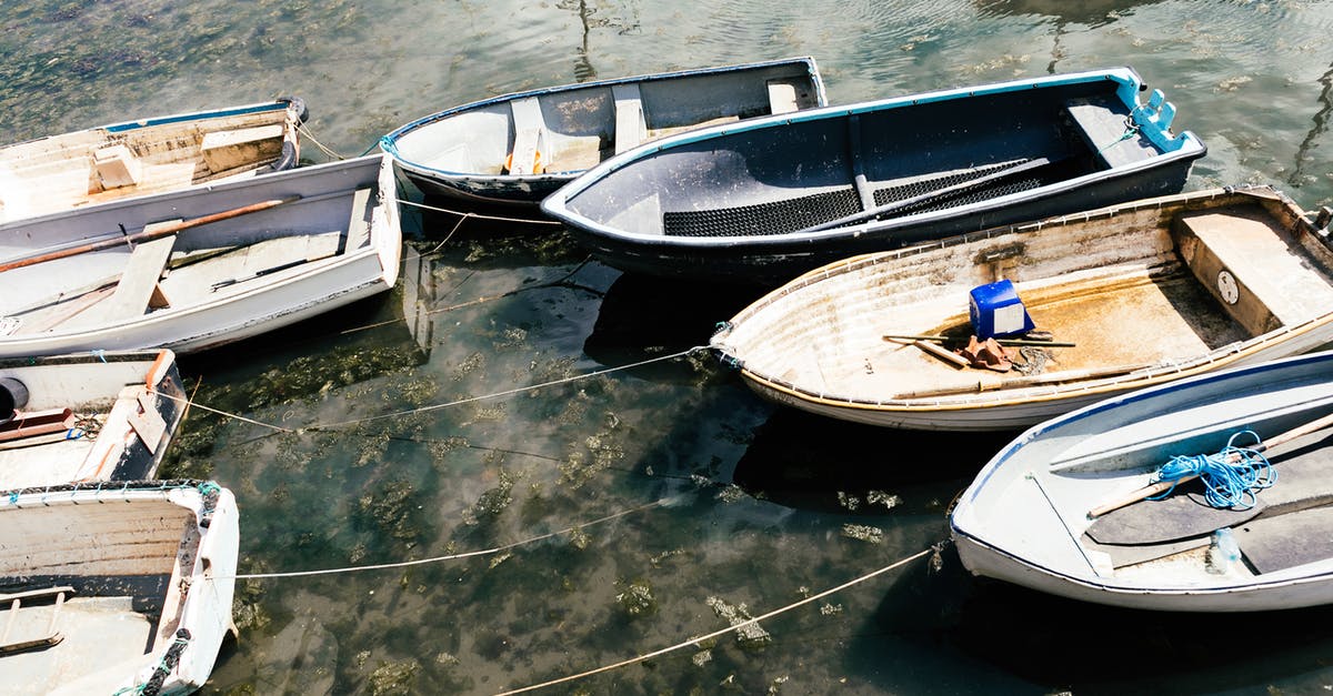 A one day trip to Milan from Zurich - From above of small simple empty boats moored to shore with long thin ropes in sunlight