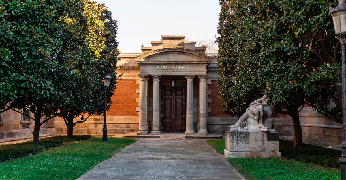 About entry in Europe [duplicate] - Facade of old library with high columns with walkway and statue in green park in Spain