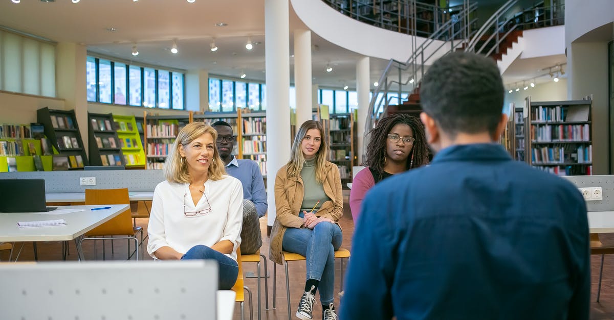 About Visa for academic conference in Dubai/Abu-Dhabi - Group of attentive diverse classmates and teacher listening carefully presentation of student at seminar in university class