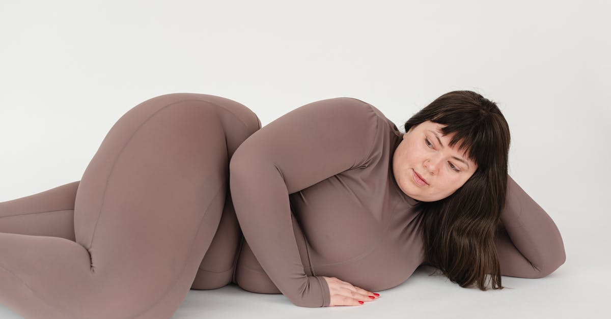 Acceptance of large bills in Denmark - High angle of serious plus size female with long hair leaning on hand while lying against white background