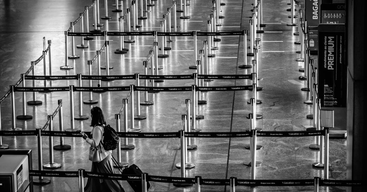 Accessing Karlsruhe from a major airport - From above black and white side view of unrecognizable female tourist with backpack and suitcase strolling on fenced passage in airport