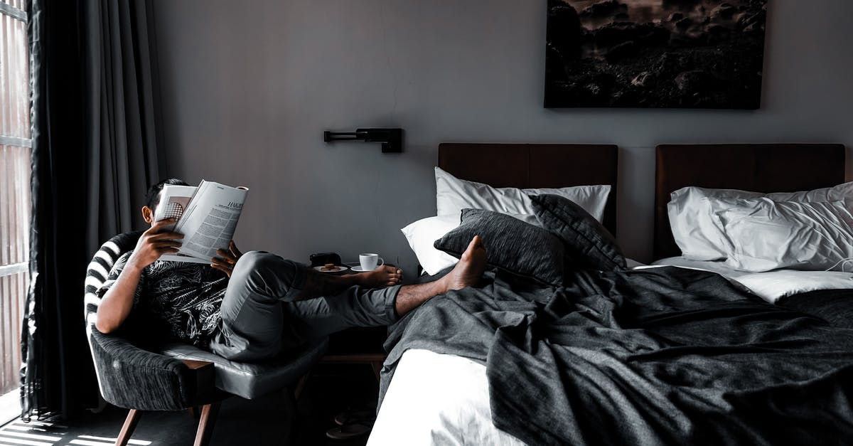 Accidentally booked hotel room twice - Man Sitting on Chair Reading Book