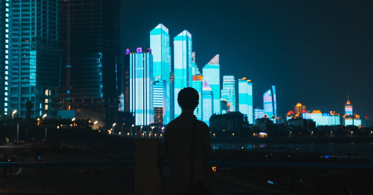 Accommodation in Rancagua, Chile for less than 30 USD/night? - Back view of anonymous male enjoying view of high modern illuminated towers of metropolis at night