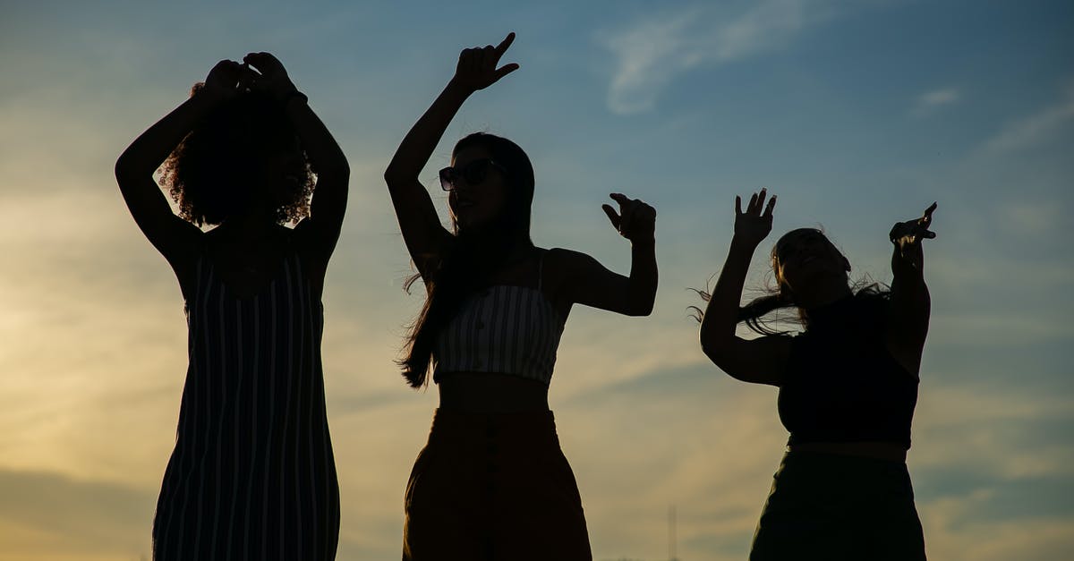 Activities in Montreal for a Bachelor party - Low angle silhouettes of unrecognizable young female friends dancing against cloudy sunset sky during open air party