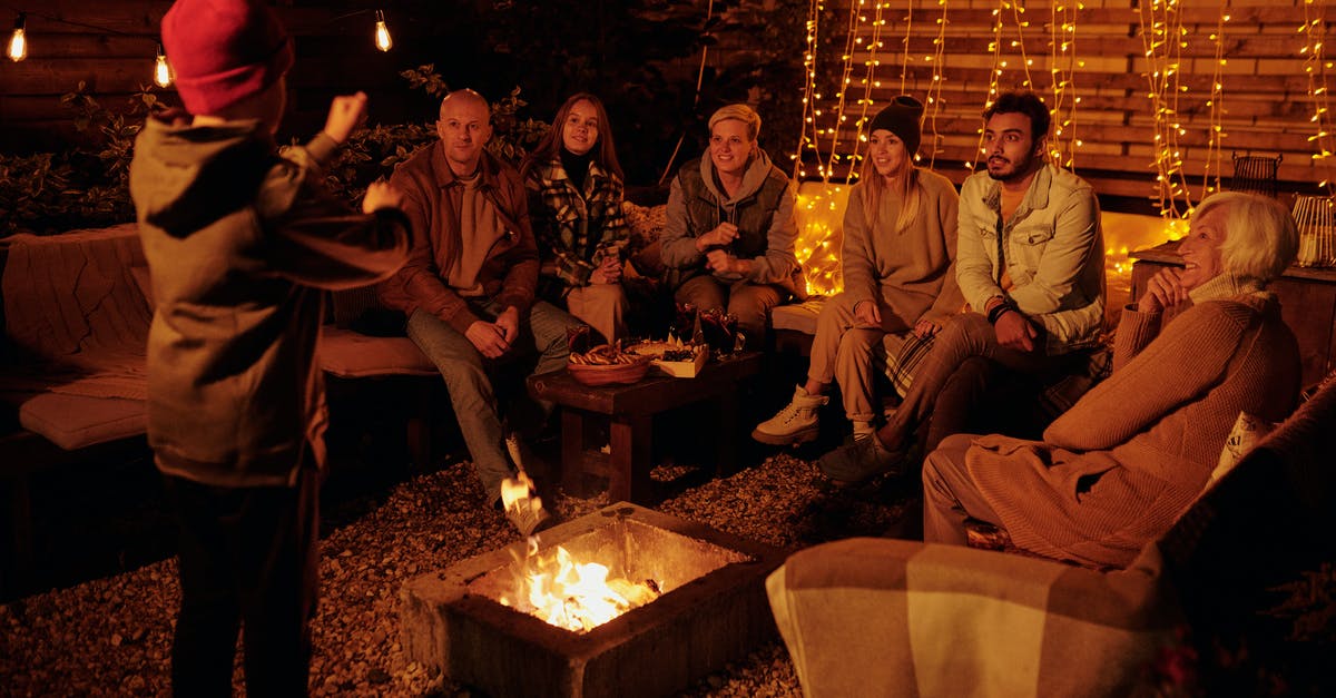 Activities in Montreal for a Bachelor party - Boy acting out charade word while playing with friends and family around backyard bonfire at night