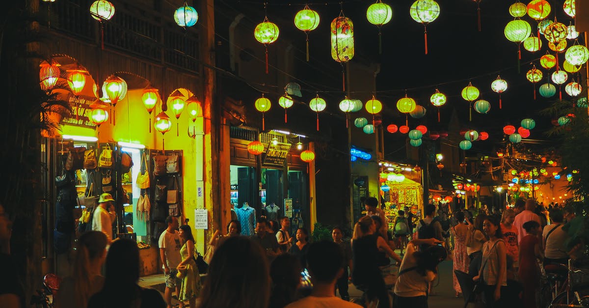 Activities in Warsaw during a public holiday [closed] - Anonymous people walking and spending time on city street decorated with Asian paper lanterns near touristic shops and cafes at night