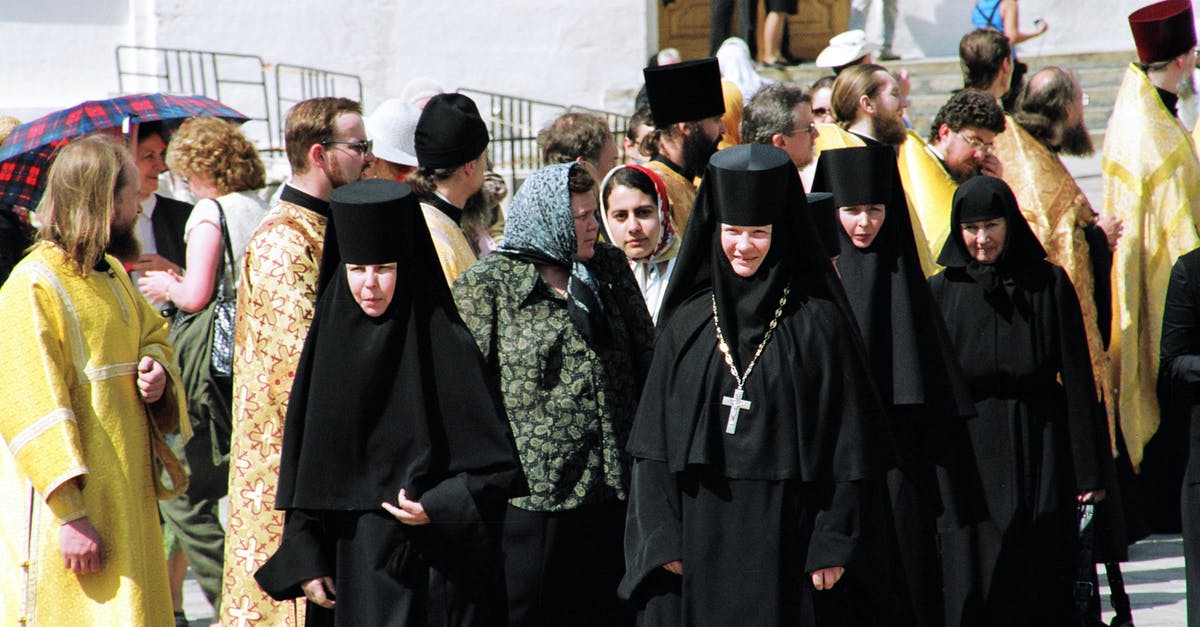 Activities in Warsaw during a public holiday [closed] - Nuns of convent wearing black clothes walking along street passing men of cloth in golden color robes and common people located near building celebrating holiday in sunny day