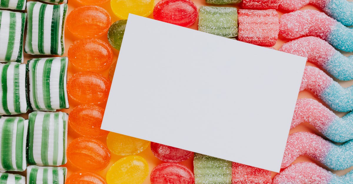 Additional information for "Split party travel arrangements" - Closeup from above of white paper card composed on rows of delicious caramel gummy jelly sweets in modern candy shop