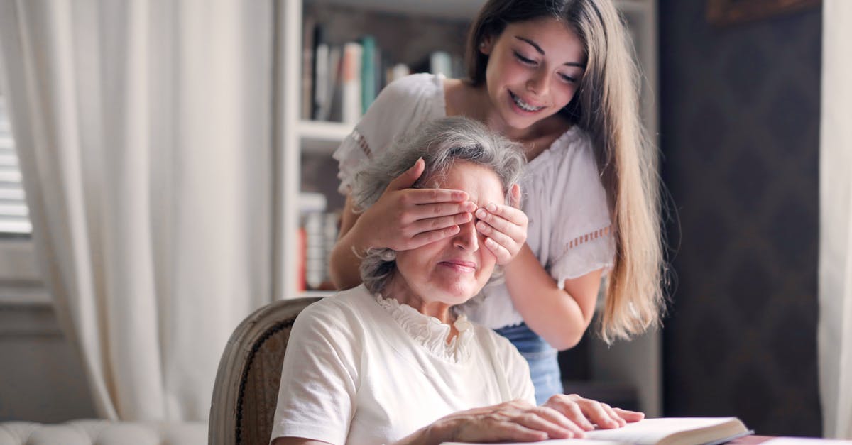 Additional luggage fee from US to Europe with a domestic connection - From below pensive gray haired woman trying to guess who closing eyes while sitting at table and reading book in light library in cottage