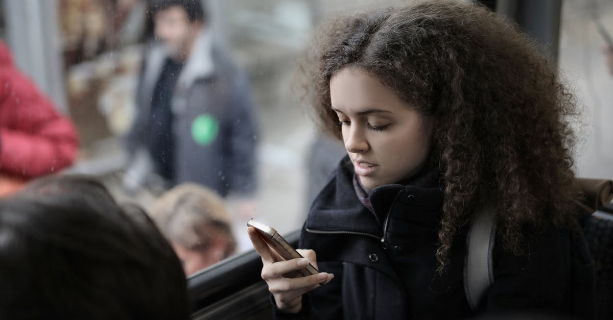 Advantages of traveling from Lima to Cusco by bus vs. plane? - From above view of serious young female traveler with backpack sitting on passenger seat in bus near window and browsing smartphone