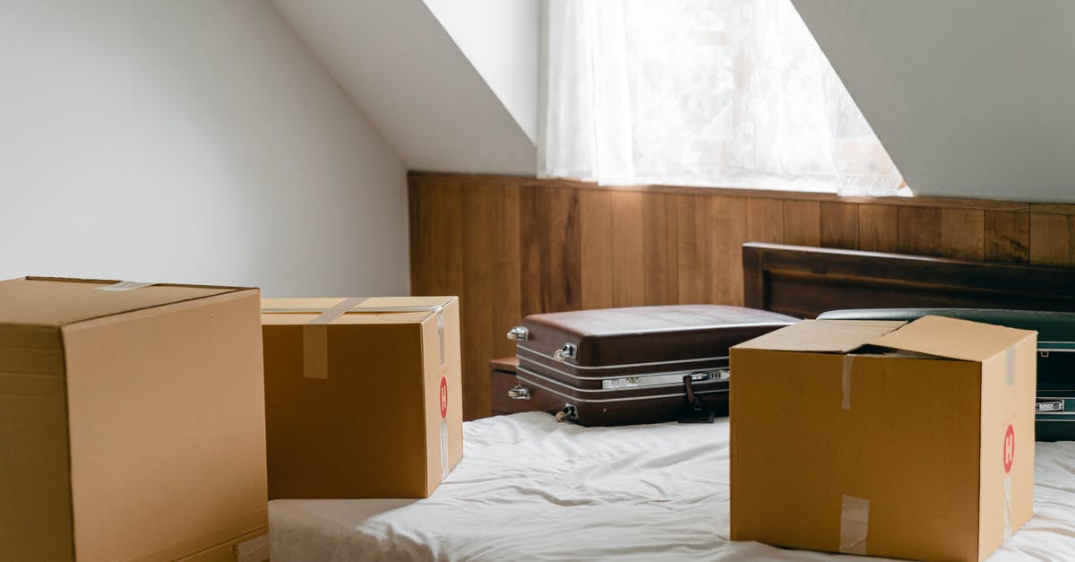 Air Canada personal item sizer size? - Small cardboard boxes and leather cases placed on bed with sheet near big box in light room of house under sloping roof