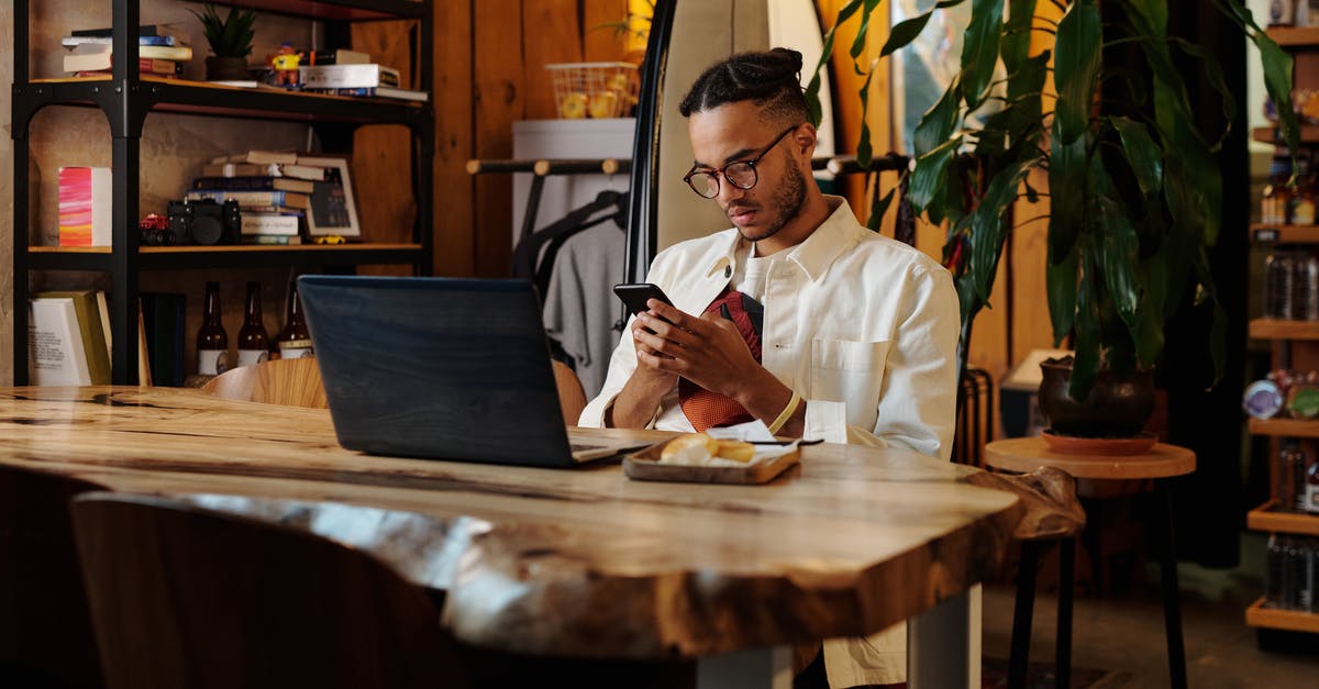 Air-conditioned cafe in Kampot, Cambodia? - Stylish Man in White Jacket and Eyeglasses using his Phone 