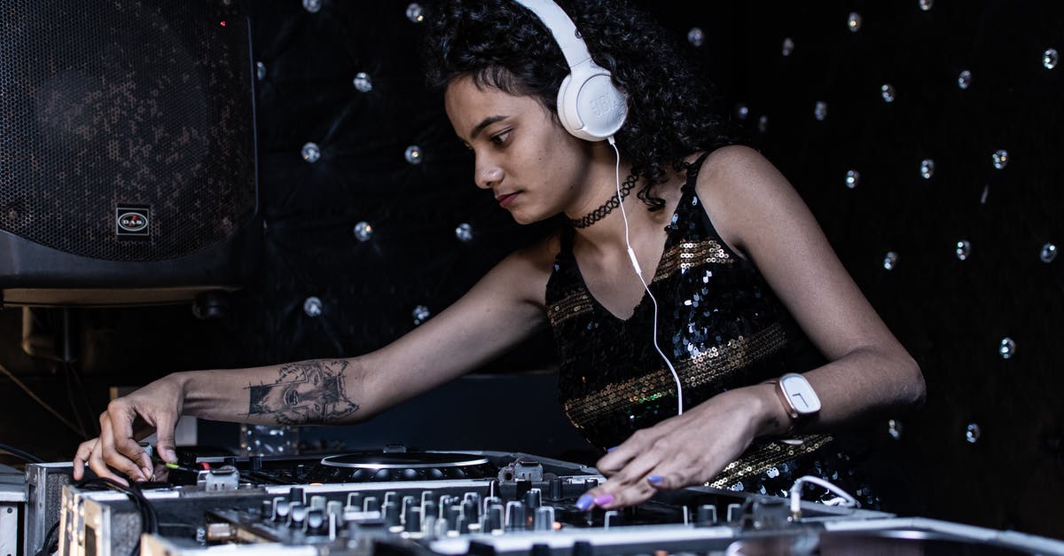 Aircraft headphone volume - Focused ethnic female DJ playing music at nightclub