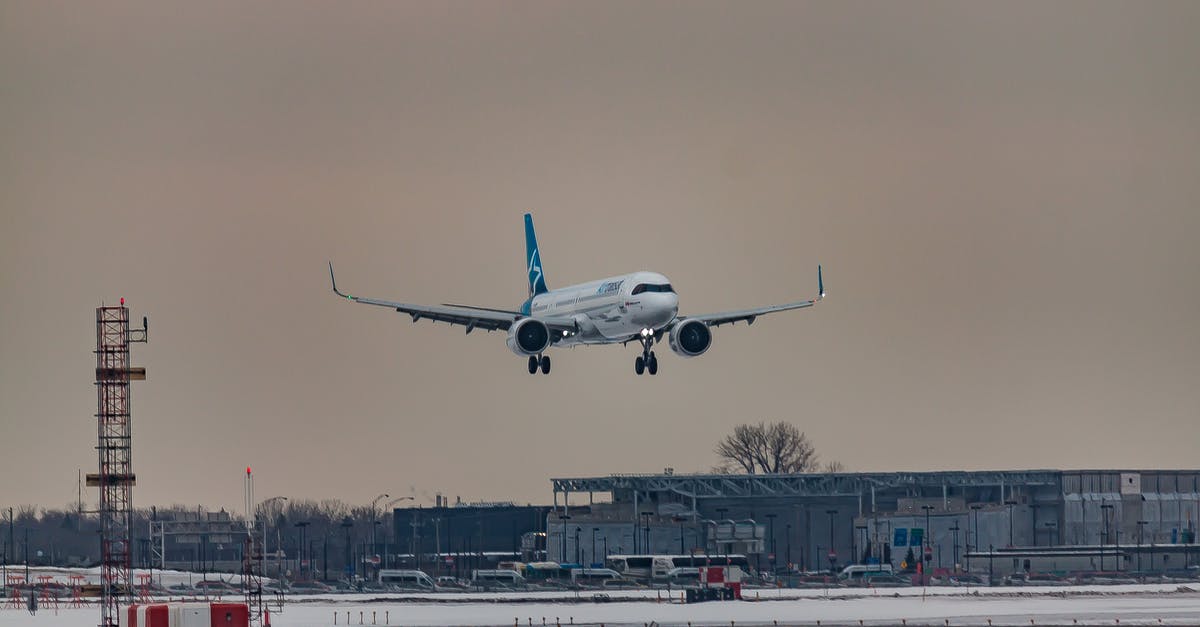 Airline flies, even though we aren't allowed to enter Canada - Powerful airplane flying over snowy terrain and preparing for landing on aerodrome airfield against cloudy sunset sky