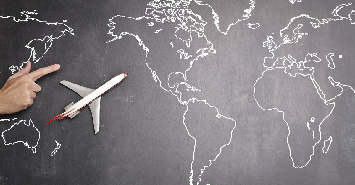 Airline pricing website with multiple destinations - Top view of miniature airplane placed on over gray world map with crop hand of anonymous person indicating direction representing travel concept