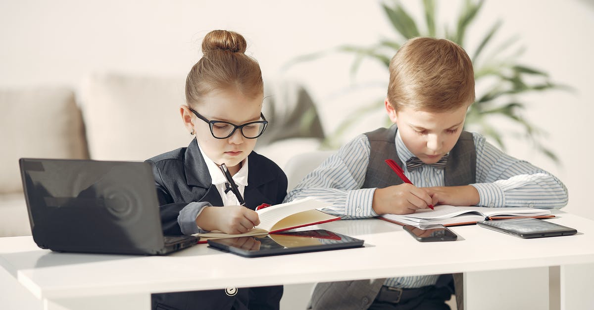 Airline responsibility during connection - Cute business children in uniform using laptop and writing information in planners while making up startup strategy in modern workspace