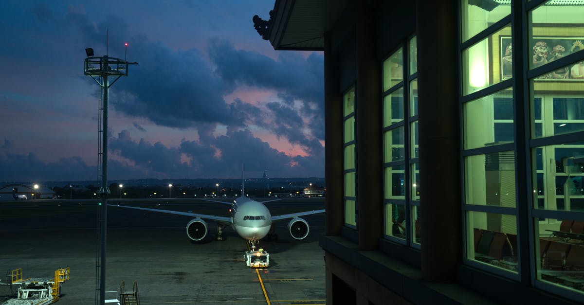 Airline responsibility during connection - Modern plane parking on stand near assigned gate in modern airport terminal at night