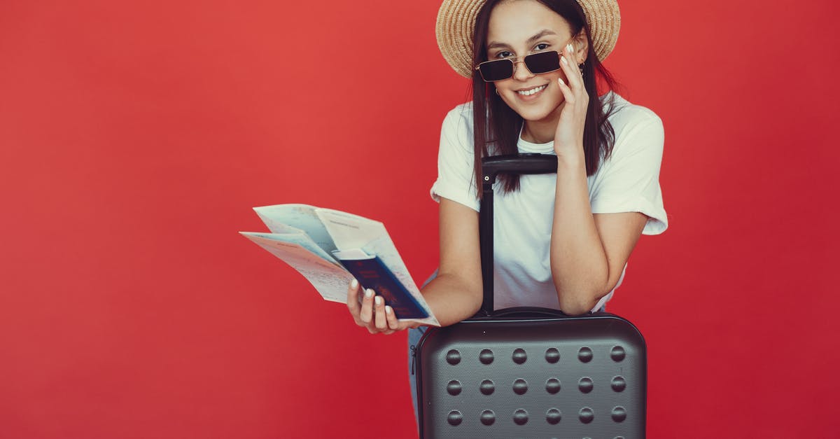 Airlines refusing check-in without return ticket - Cheerful female tourist checking tickets on red background