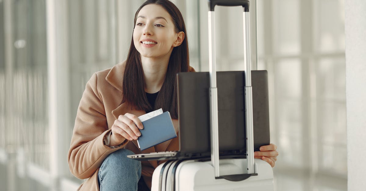 Airlines refusing check-in without return ticket - Positive woman with passport using laptop on luggage in airport