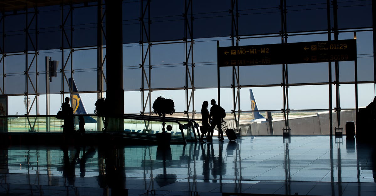 Airport security checkpoint controlling carry-on luggage amount? - Silhouette of People Walking at the Airport