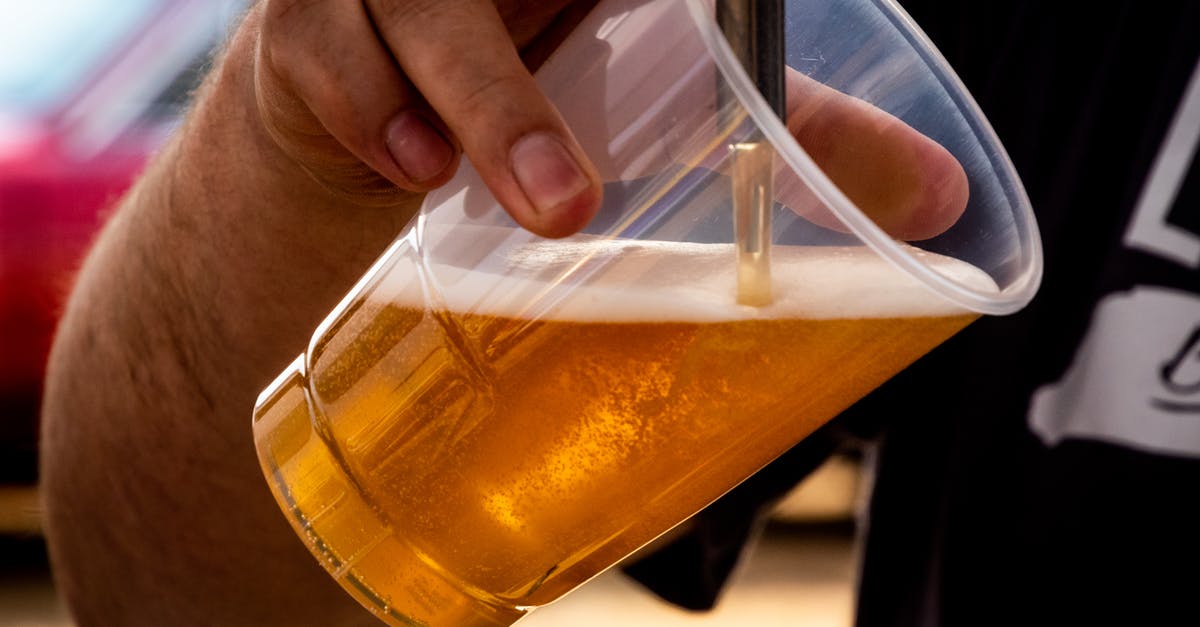 Alcohol as necessary medicine when visiting dry countries? - Person Pouring Beer on Clear Cup