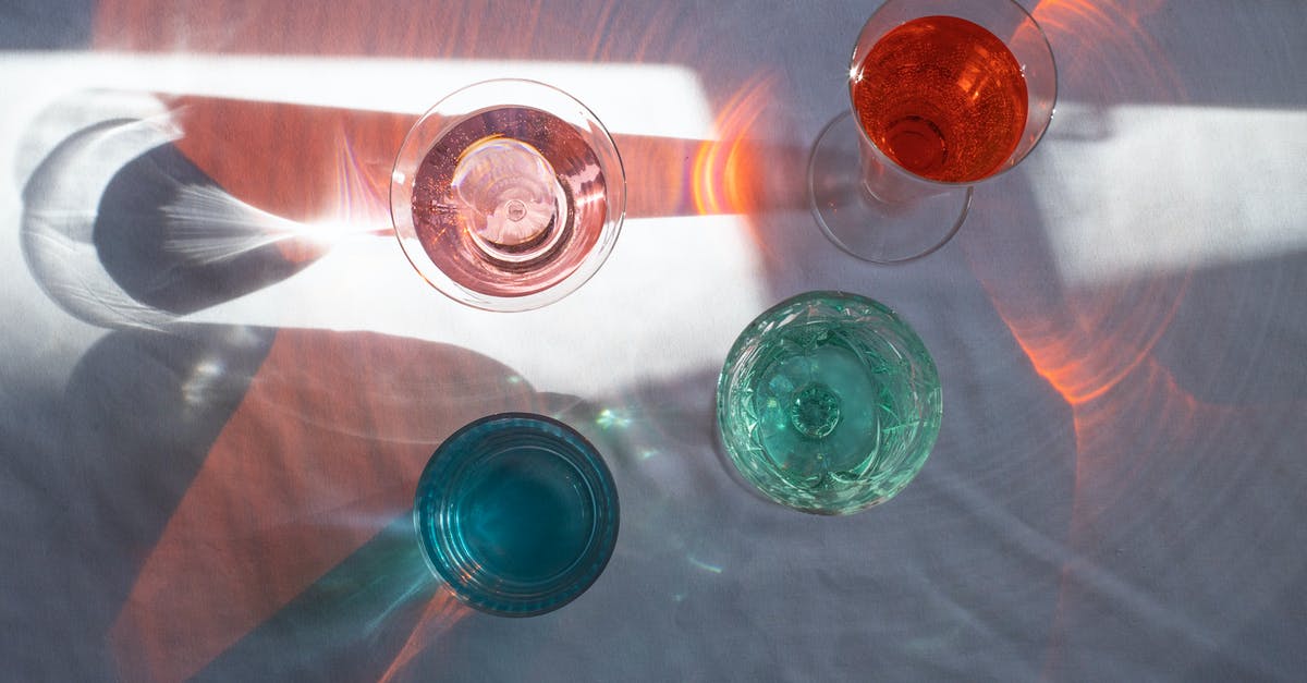 Alcohol when flying to Singapore from EU through Malaysia - Top view of transparent glasses filled with different beverages and placed at sun beam