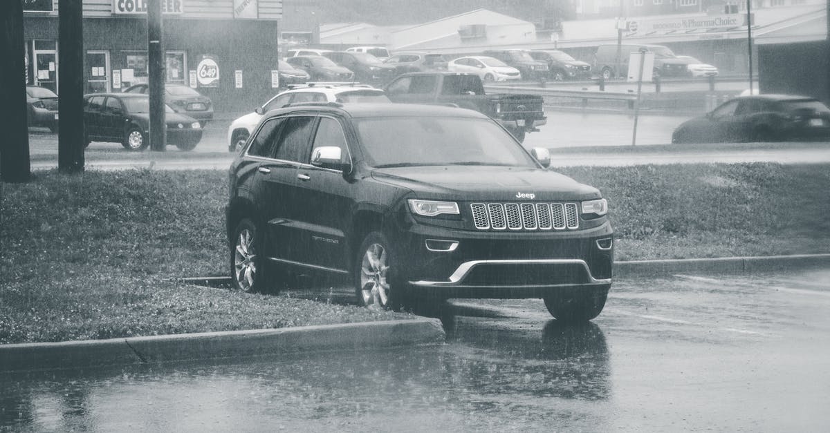 All day vs street parking in Edinburgh and Glasgow - Black and white of big black modern off road sUV automobile parked on wet asphalt in city under rain in daytime