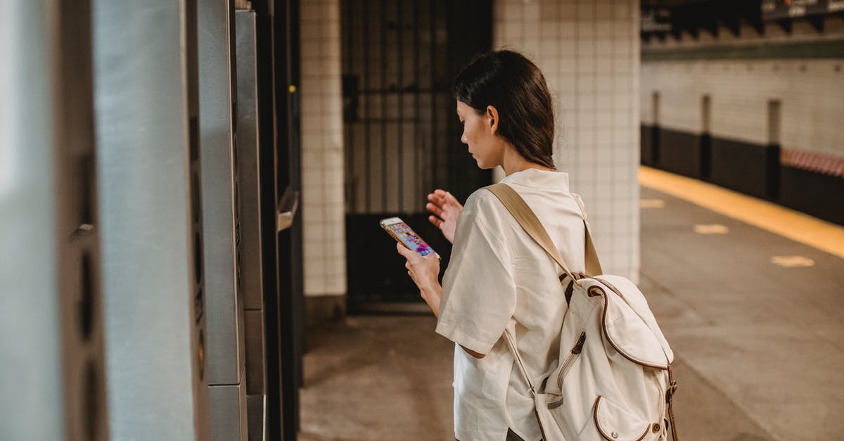 Almaty to Urumqi by connecting train (via Altynkol and Khorgas) - Side view of young concentrated ethnic female in casual clothes and backpack browsing mobile phone while standing on platform of subway station