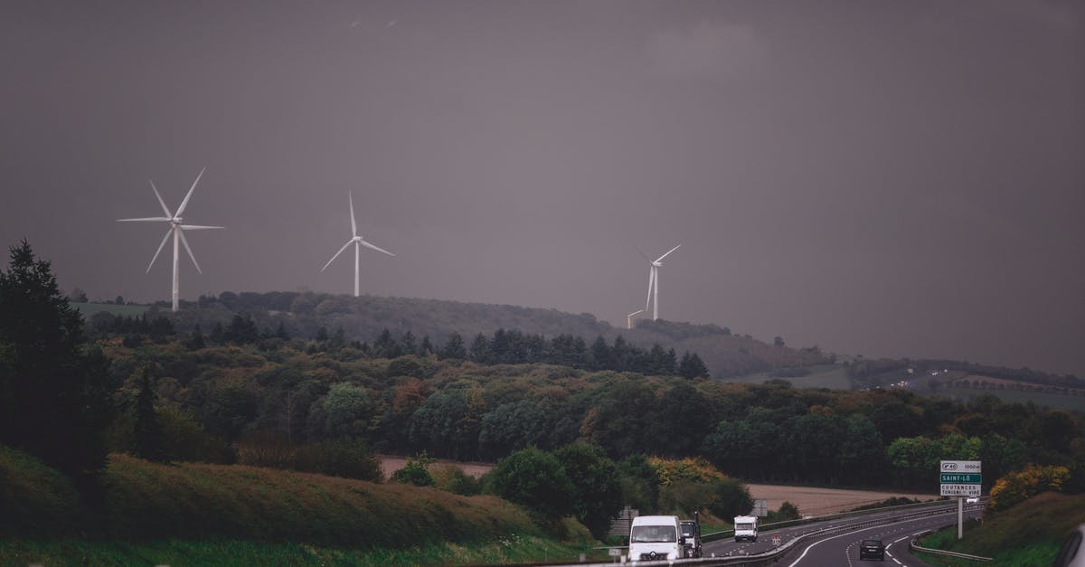 Alternate routes Almaty to Novosibirsk - Asphalt highway running through grassy lush valley with modern wind turbine generators under gloomy overcast sky