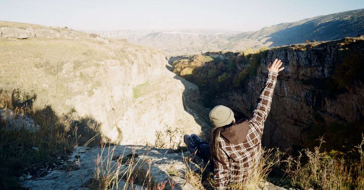 Am I a repeat traveler in terms of ESTA? - Person in Brown and White Plaid Shirt Sitting on Rocky Cliff