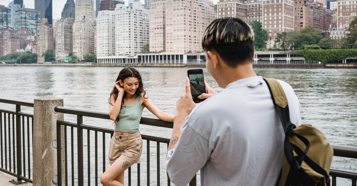 Am I affected by the travel ban - getting a US visa for Syrian citizens? - Young man photographing girlfriend on smartphone during date in city downtown near river
