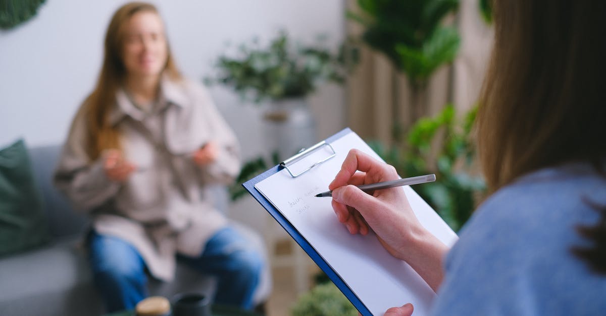 Am I being scammed? (UK visit visa refusal) - Unrecognizable professional female psychologist writing on clipboard while sitting against client on blurred background during psychotherapy session in light office