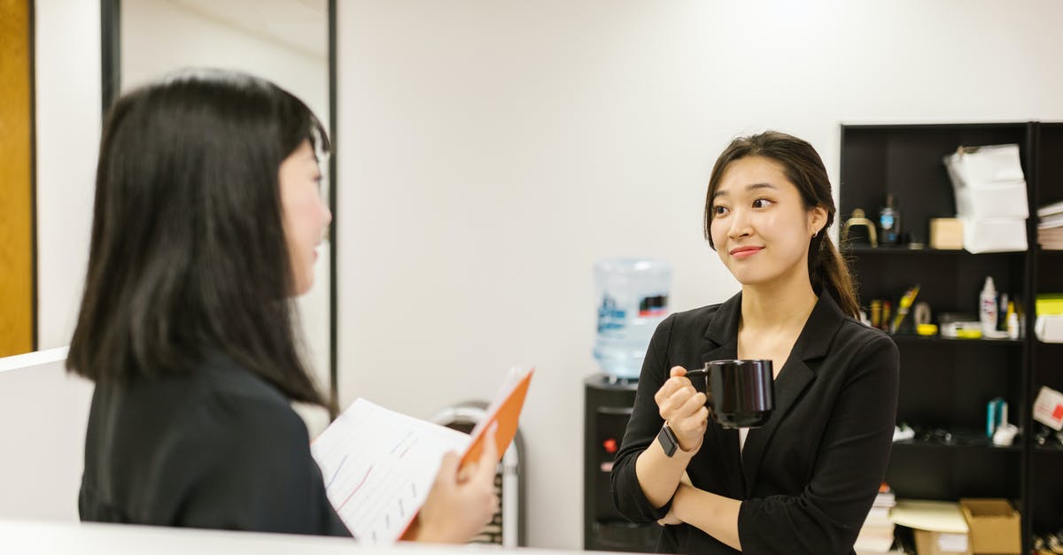 Am I over-staying in the Philippines? Japanese Dual citizen - A Woman Listening to a Coworker while Holding a Mug at an Office