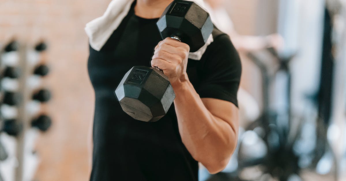 Am I too heavy for Chinese hard sleeper trains? - Unrecognizable strong male with towel wearing black activewear lifting heavy dumbbell during intense training in fitness studio with special equipment on blurred background