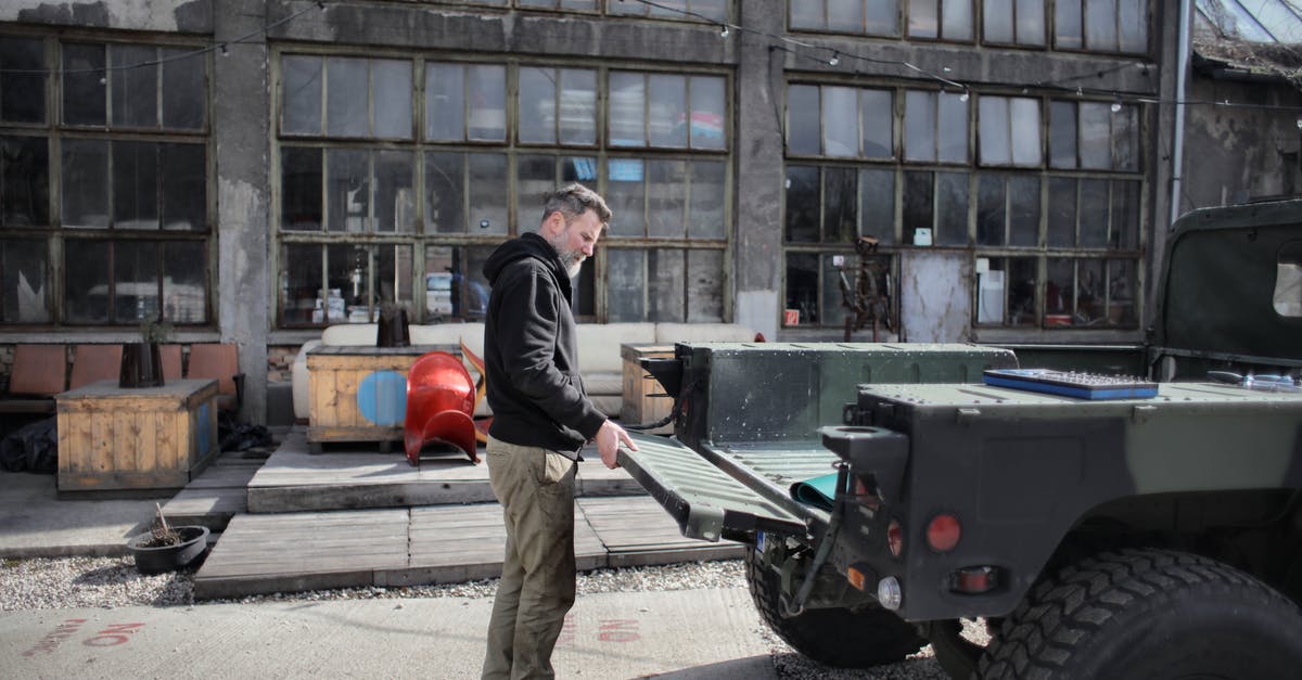 Amazon/Ebay pickup locations in Frankfurt/Munich/Vienna airport? - Side view of brutal male mechanic in casual outfit closing car trunk while standing on background of shabby building