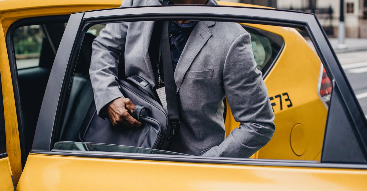 Amsterdam: parking a rental car downtown - Crop African American male in formal suit sitting in yellow taxi car parked on city street