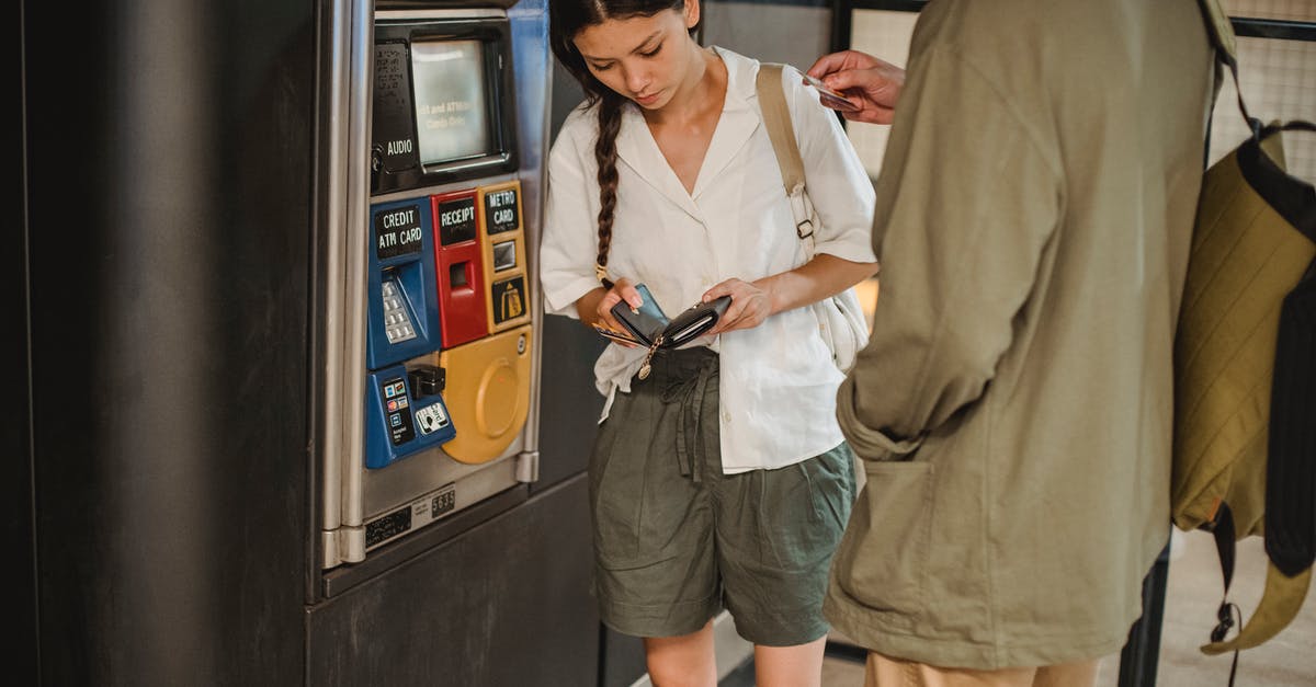 Amtrak - Why can she not buy two tickets for herself? - Calm young couple wearing casual clothes standing together near ticket vending machine with wallet in hands in underground