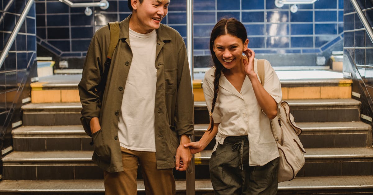 Amtrak Rail Pass questions - Happy Asian couple in casual clothes holding hands and walking together in underground hallway