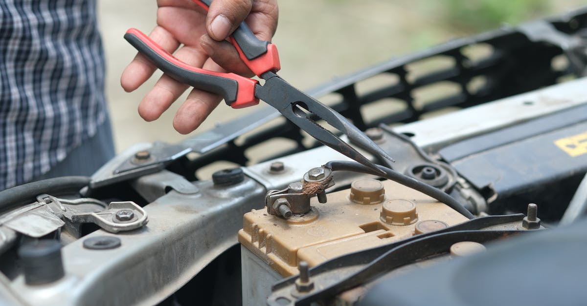 An extra battery in a hand luggage? - A Person Holding Red and Black Hand Tool